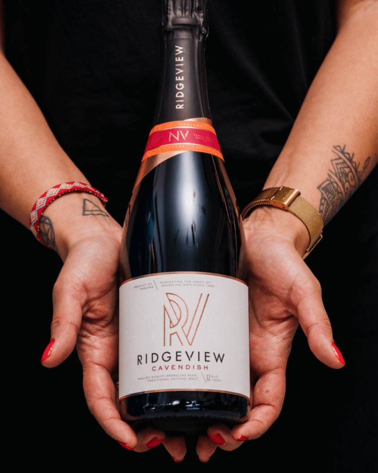 Ridgeview Wine Estate, English Sparkling Wine, Cavendish bottle held in hands with tattoos, watches and red nail varnish